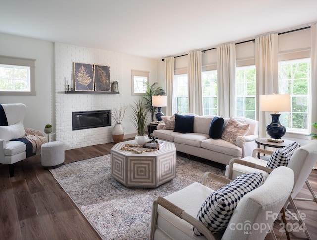 living room featuring a brick fireplace, a healthy amount of sunlight, and hardwood / wood-style flooring