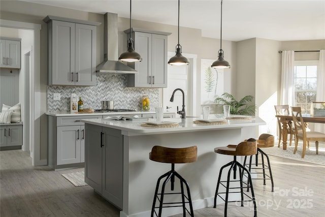 11330 James Coy Rd Covington, Unit Covington, Davidson, NC 28036 - kitchen featuring gray cabinets, wall chimney exhaust hood, tasteful backsplash, light countertops, and light wood finished floors