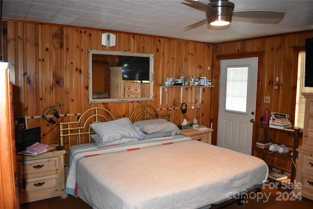 bedroom featuring wood walls and ceiling fan