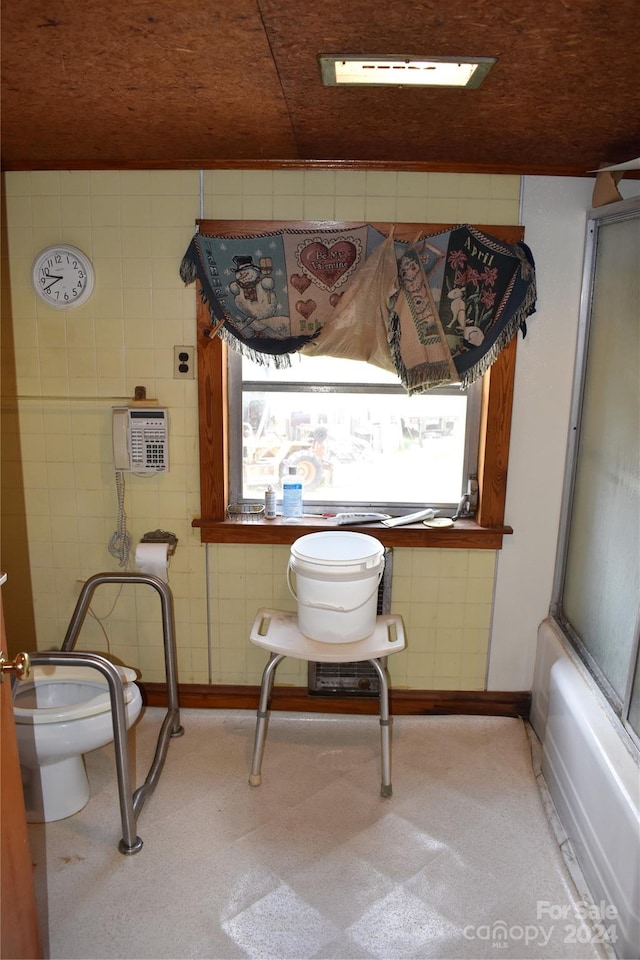 bathroom with bath / shower combo with glass door, tile walls, and toilet