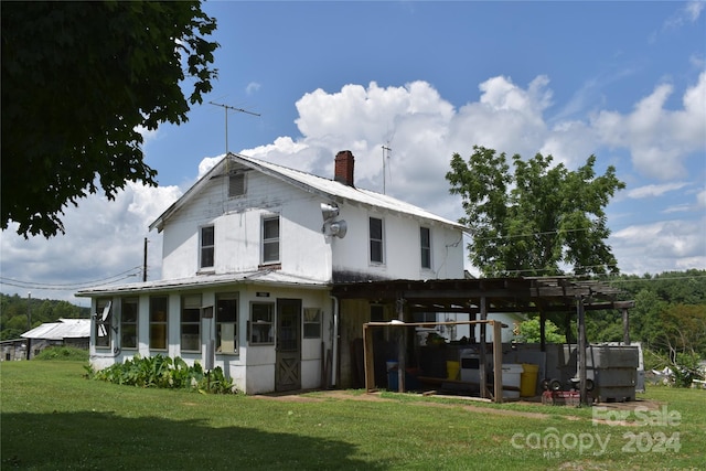 back of property with a sunroom, a pergola, and a yard