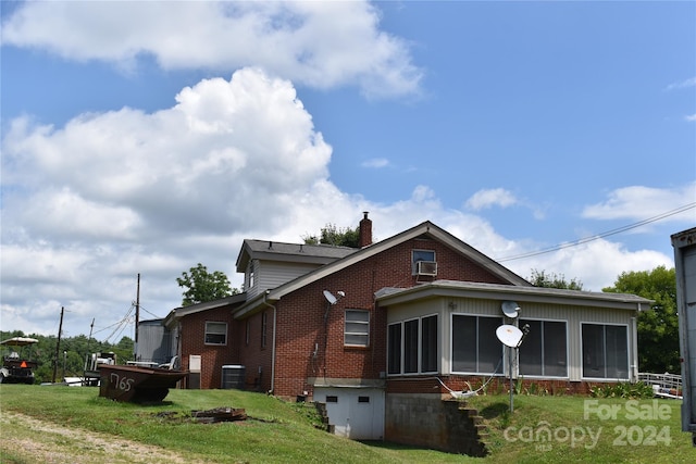 view of side of property featuring a yard, a sunroom, and central air condition unit