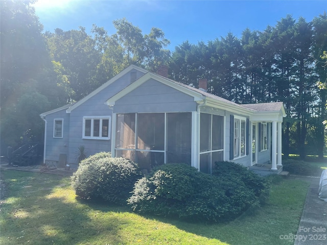 view of front facade featuring a sunroom and a front lawn