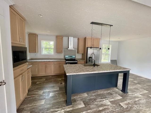 kitchen featuring stainless steel appliances, wall chimney range hood, a textured ceiling, decorative light fixtures, and a kitchen island with sink