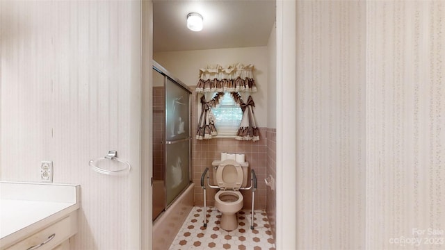 bathroom featuring toilet, tile flooring, vanity, and tile walls