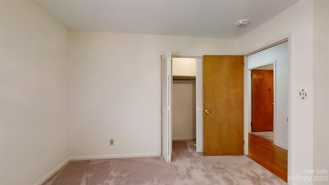 unfurnished bedroom with light colored carpet and a closet