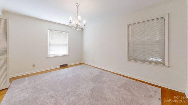 empty room with an inviting chandelier and light hardwood / wood-style floors