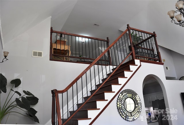 staircase featuring a towering ceiling and a chandelier