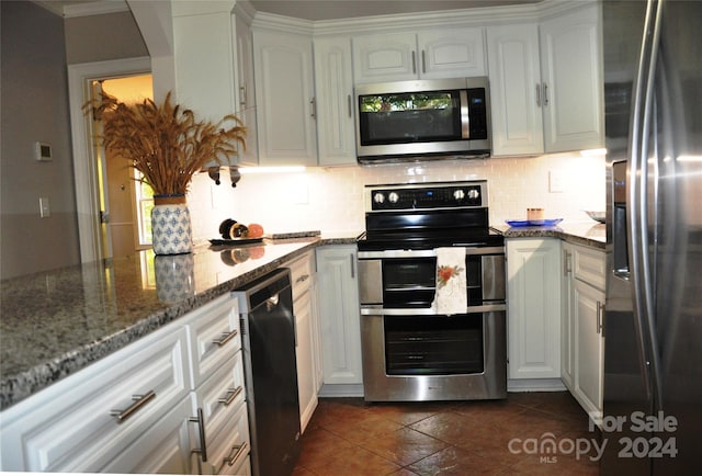 kitchen featuring dark stone counters, tasteful backsplash, stainless steel appliances, and white cabinets