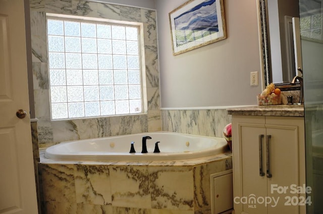 bathroom with tiled tub and vanity