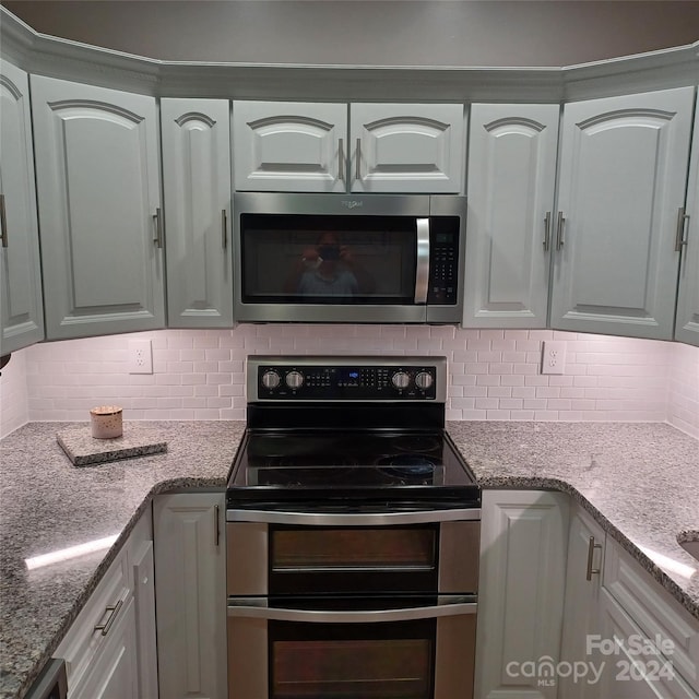 kitchen with light stone counters, white cabinetry, stainless steel appliances, and tasteful backsplash