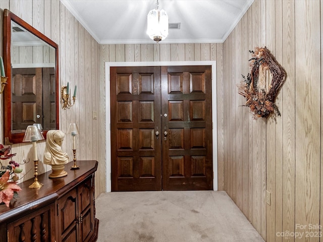 entrance foyer with wooden walls, carpet flooring, and crown molding