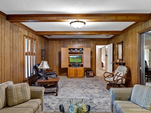 living room with carpet flooring, beamed ceiling, wood walls, and a textured ceiling