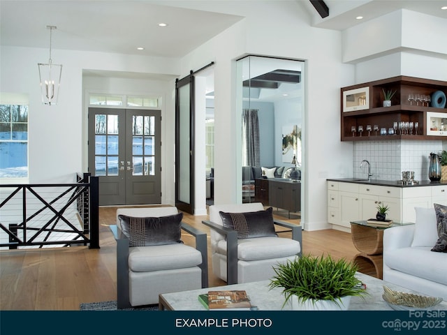 living room with a notable chandelier, light wood-type flooring, plenty of natural light, and a barn door