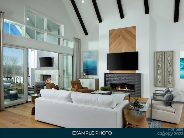 living room featuring beam ceiling, high vaulted ceiling, light wood-type flooring, and a fireplace