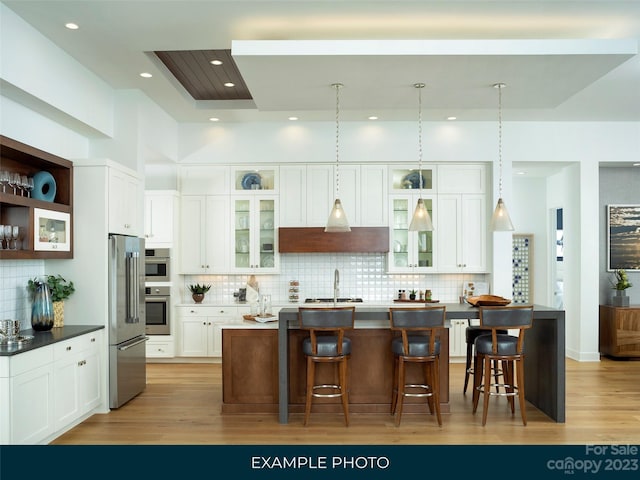 kitchen with appliances with stainless steel finishes, tasteful backsplash, an island with sink, and a breakfast bar area