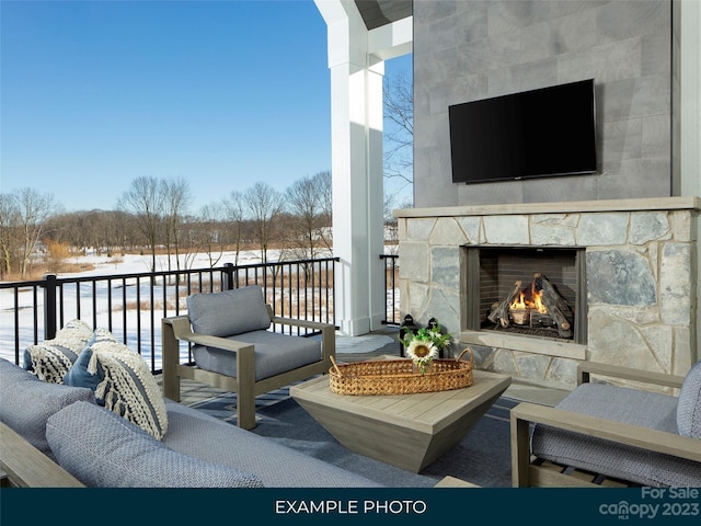 snow covered back of property featuring an outdoor stone fireplace