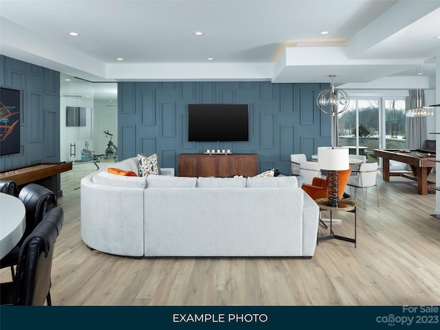 living room with pool table, a chandelier, and light wood-type flooring