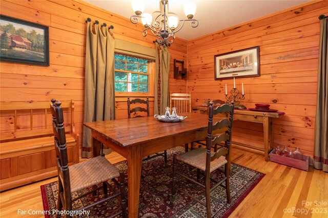 dining room with an inviting chandelier, wood walls, and light hardwood / wood-style floors