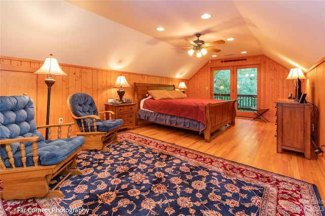 bedroom with access to exterior, ceiling fan, wooden walls, light hardwood / wood-style flooring, and lofted ceiling