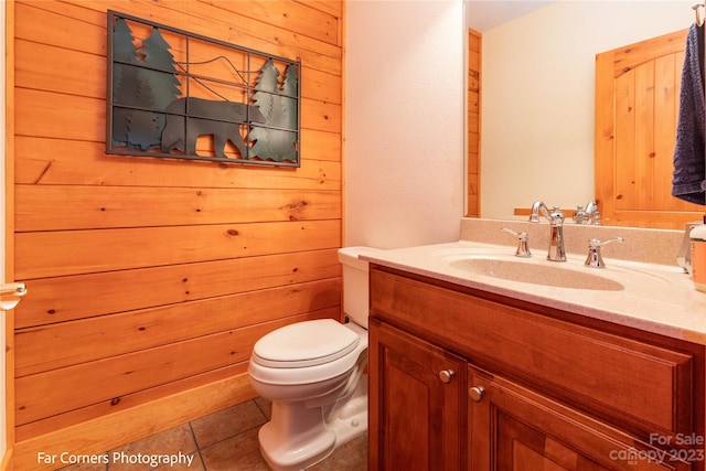 bathroom with oversized vanity, toilet, tile floors, and wooden walls