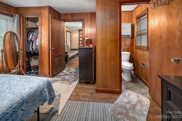 bathroom with hardwood / wood-style floors, toilet, wood walls, and vanity