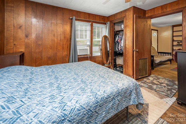 bedroom featuring dark hardwood / wood-style flooring, wooden walls, and ceiling fan