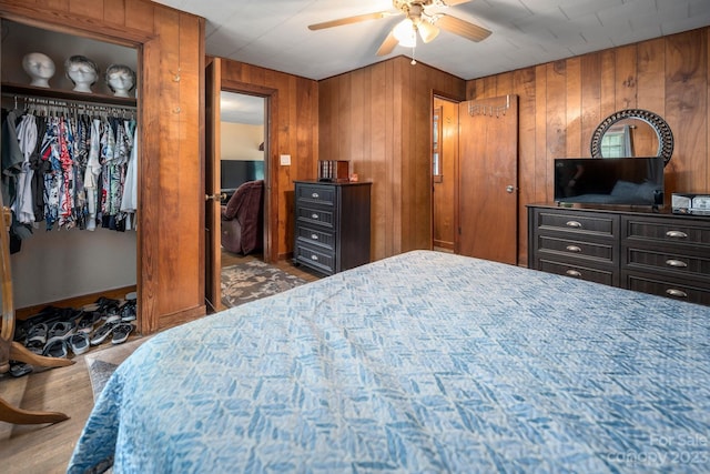 bedroom featuring ceiling fan, dark wood-type flooring, and wood walls