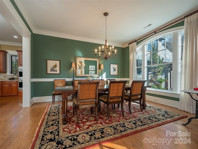 dining room featuring a notable chandelier, crown molding, and light hardwood / wood-style flooring