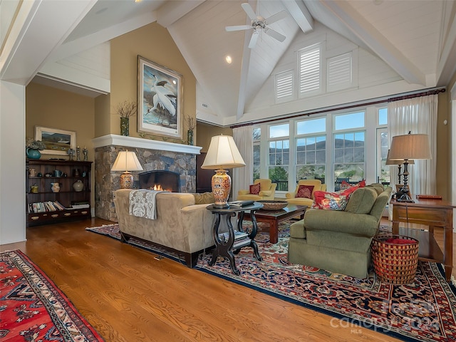 living room featuring high vaulted ceiling, ceiling fan, hardwood / wood-style floors, a fireplace, and beam ceiling