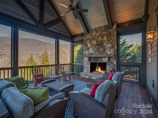 sunroom featuring lofted ceiling with beams, wood ceiling, a fireplace, and ceiling fan