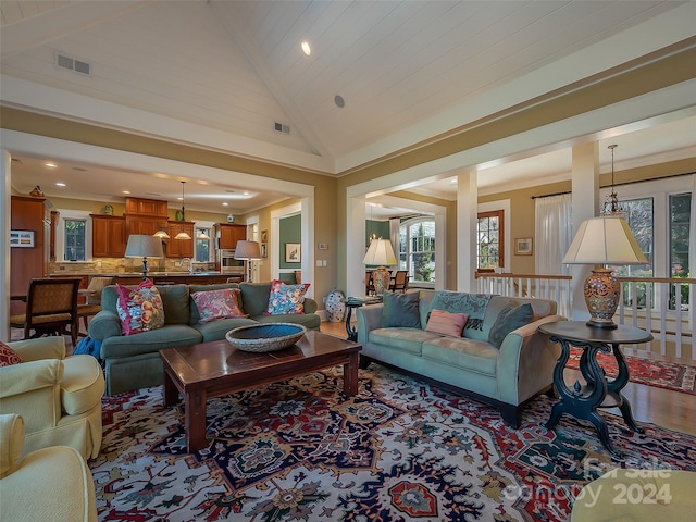 living room featuring crown molding, high vaulted ceiling, and light hardwood / wood-style floors