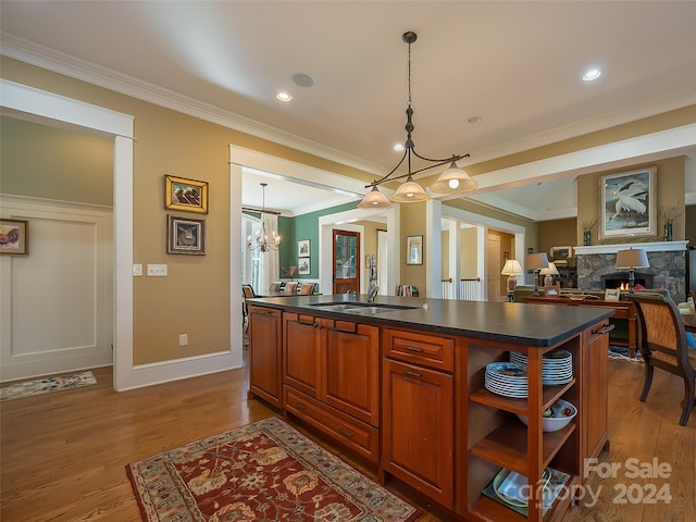 kitchen with a chandelier, a stone fireplace, light hardwood / wood-style flooring, pendant lighting, and ornamental molding