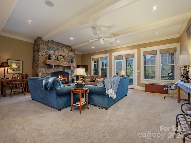 carpeted living room featuring ceiling fan, crown molding, beamed ceiling, and a stone fireplace