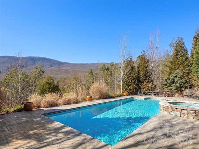 view of pool featuring an in ground hot tub, a mountain view, and a patio