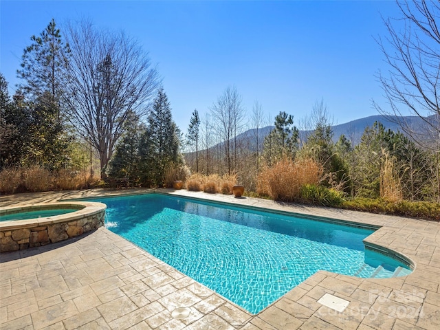 view of swimming pool with a patio area, an in ground hot tub, and a mountain view