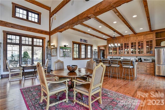 dining area featuring beamed ceiling, a chandelier, and light wood-type flooring