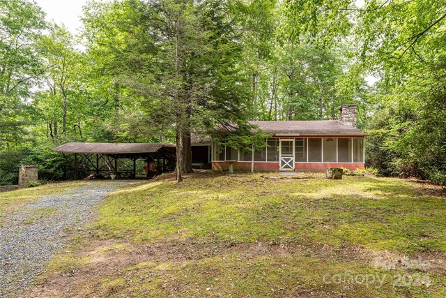 view of front facade with a sunroom, a carport, and a front yard