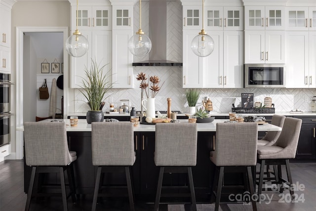 kitchen with stainless steel appliances, wall chimney exhaust hood, white cabinets, and light countertops