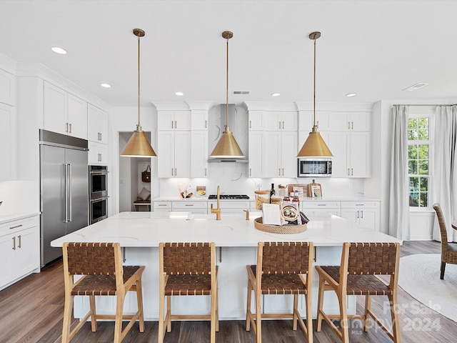 kitchen with a breakfast bar area, an island with sink, stainless steel appliances, white cabinetry, and wall chimney exhaust hood