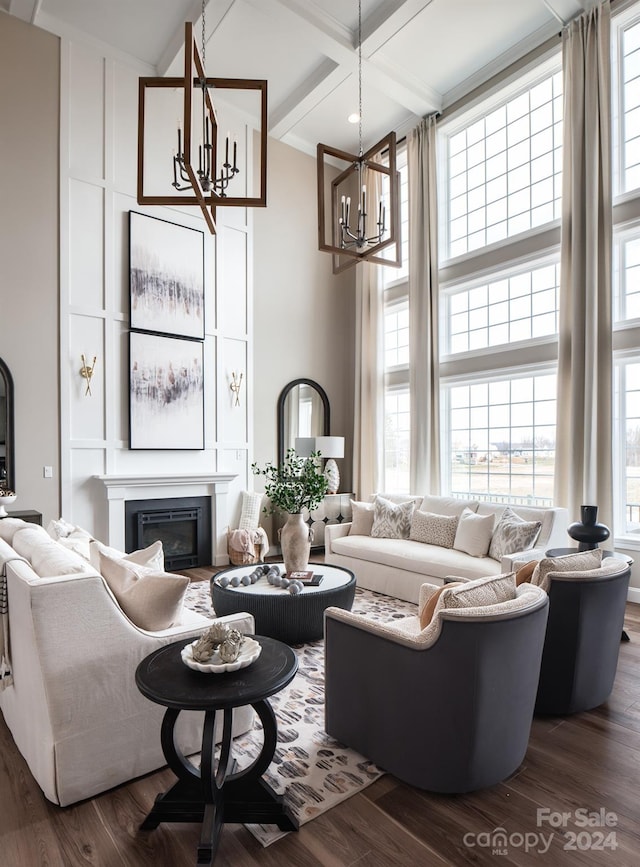 living room with a glass covered fireplace, a chandelier, a towering ceiling, and dark wood-style flooring