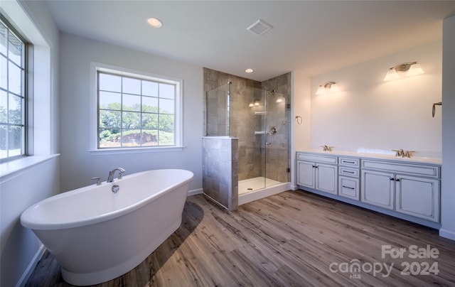 bathroom featuring visible vents, a freestanding tub, a sink, wood finished floors, and a shower stall