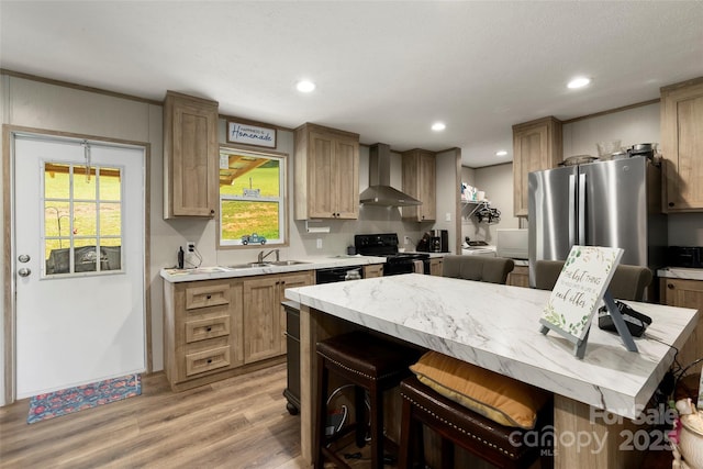 kitchen featuring a kitchen island, sink, a breakfast bar area, black appliances, and wall chimney exhaust hood