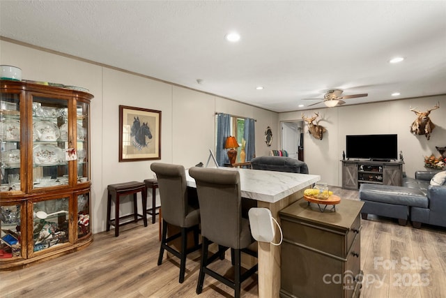 dining area with ceiling fan, ornamental molding, and light wood-type flooring