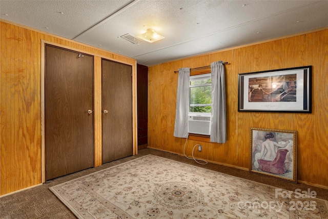 unfurnished bedroom featuring carpet floors, cooling unit, wood walls, and a closet