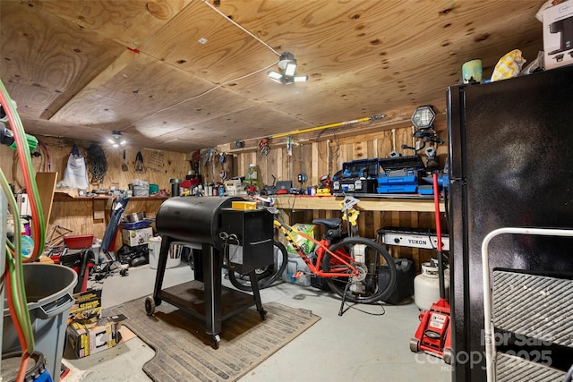 interior space featuring black refrigerator, wood walls, wood ceiling, and a workshop area