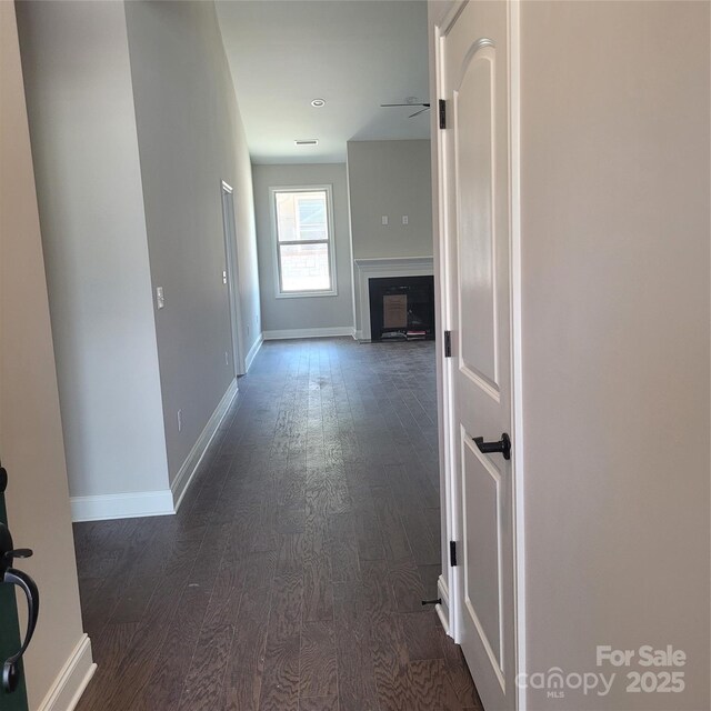 corridor featuring baseboards and dark wood-type flooring