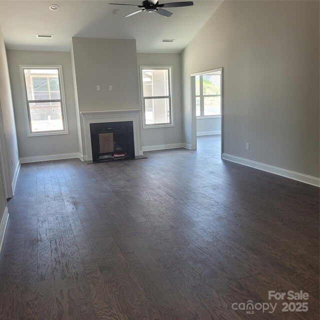 unfurnished living room featuring visible vents, a fireplace with flush hearth, dark wood-style floors, baseboards, and lofted ceiling