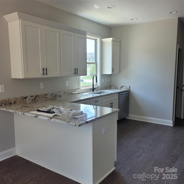 kitchen with a sink, dark wood-style floors, dishwasher, and a peninsula