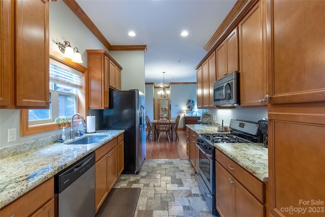 kitchen with hanging light fixtures, appliances with stainless steel finishes, sink, a chandelier, and crown molding